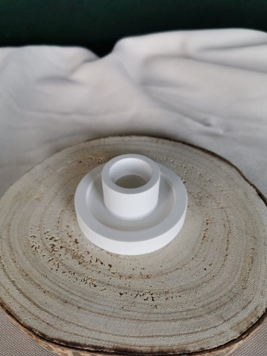 Weißer, handgefertigter Kerzenhalter aus Keramik mit klarer, geometrischer Form auf Holzuntergrund – minimalistisches Wohnaccessoire.