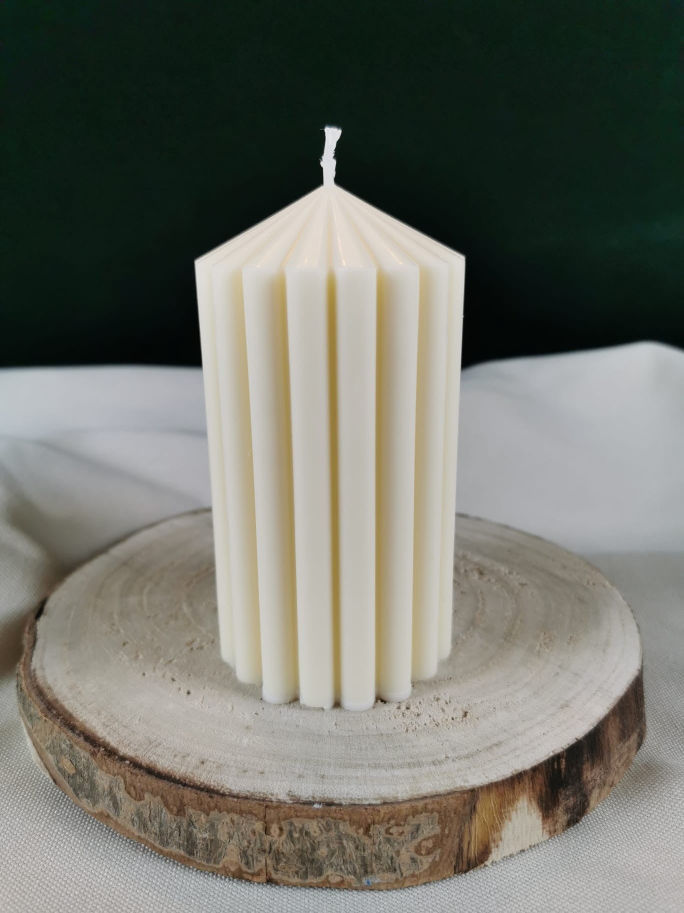 „Handgefertigte cremefarbene Ornament-Stumpenkerze aus Rapswachs mit filigranem Muster auf Natursteinplatte“