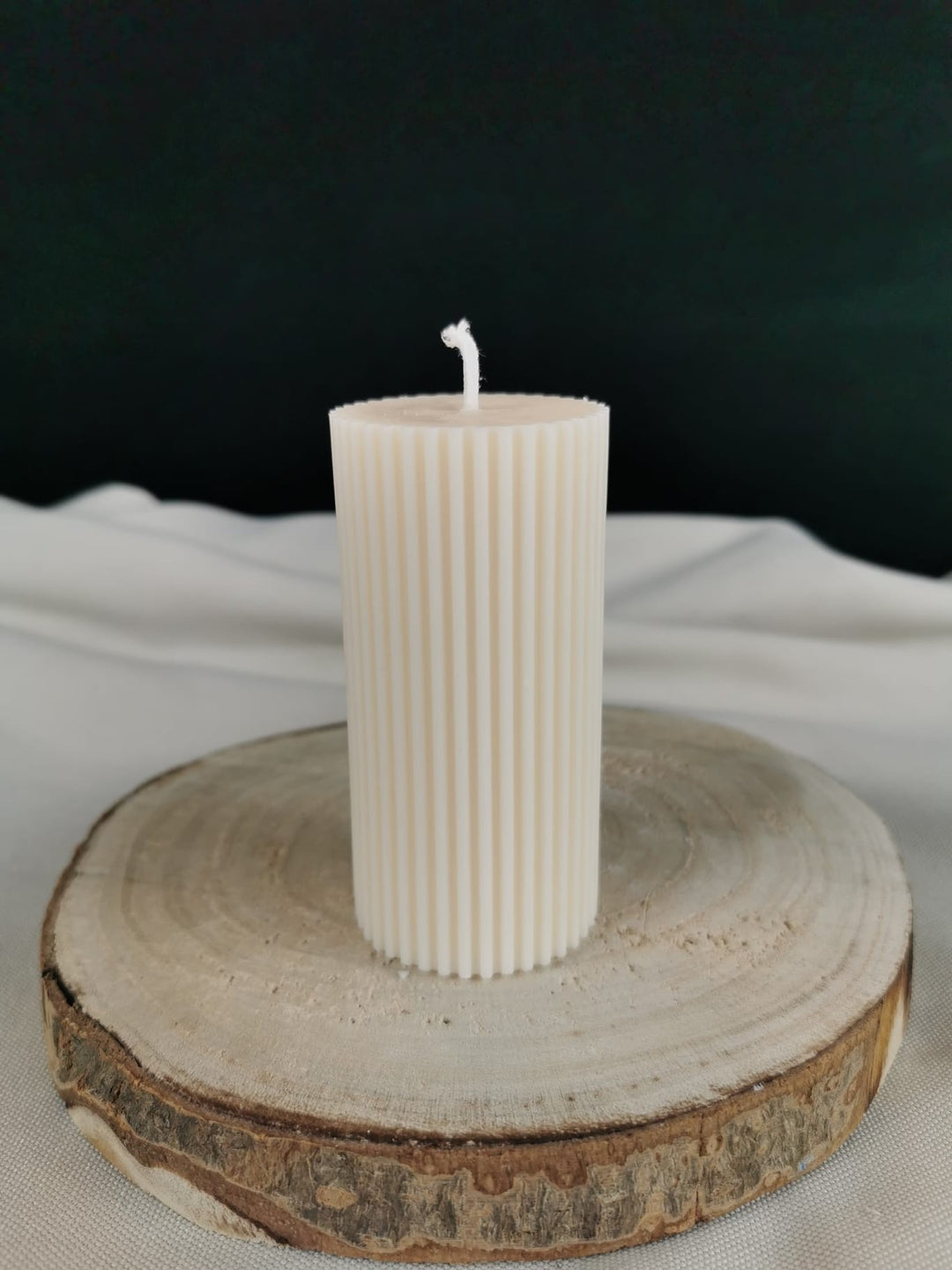 Handgegossene Ornament Stumpenkerze aus naturreinem Rapswachs mit feinem winterlichen Muster, dekorativ auf Holz platziert.