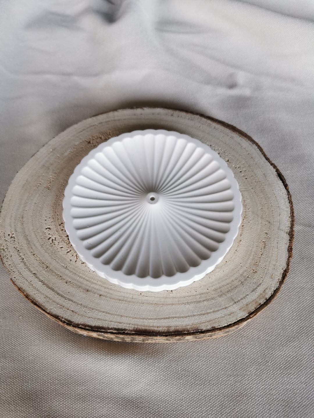 Weißer, handgefertigter Räucherstäbchenhalter aus Keramik mit strukturierter Oberfläche, platziert auf Holzuntergrund – minimalistisches, achtsames Wohnaccessoire