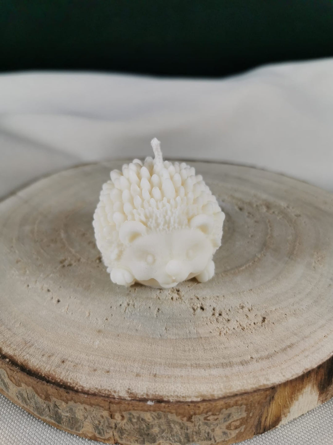 „Handgefertigte weiße Igel-Kerze aus natürlichem Rapswachs auf einer Holzplatte – detailreiche Winter- und Weihnachtsdekoration.“