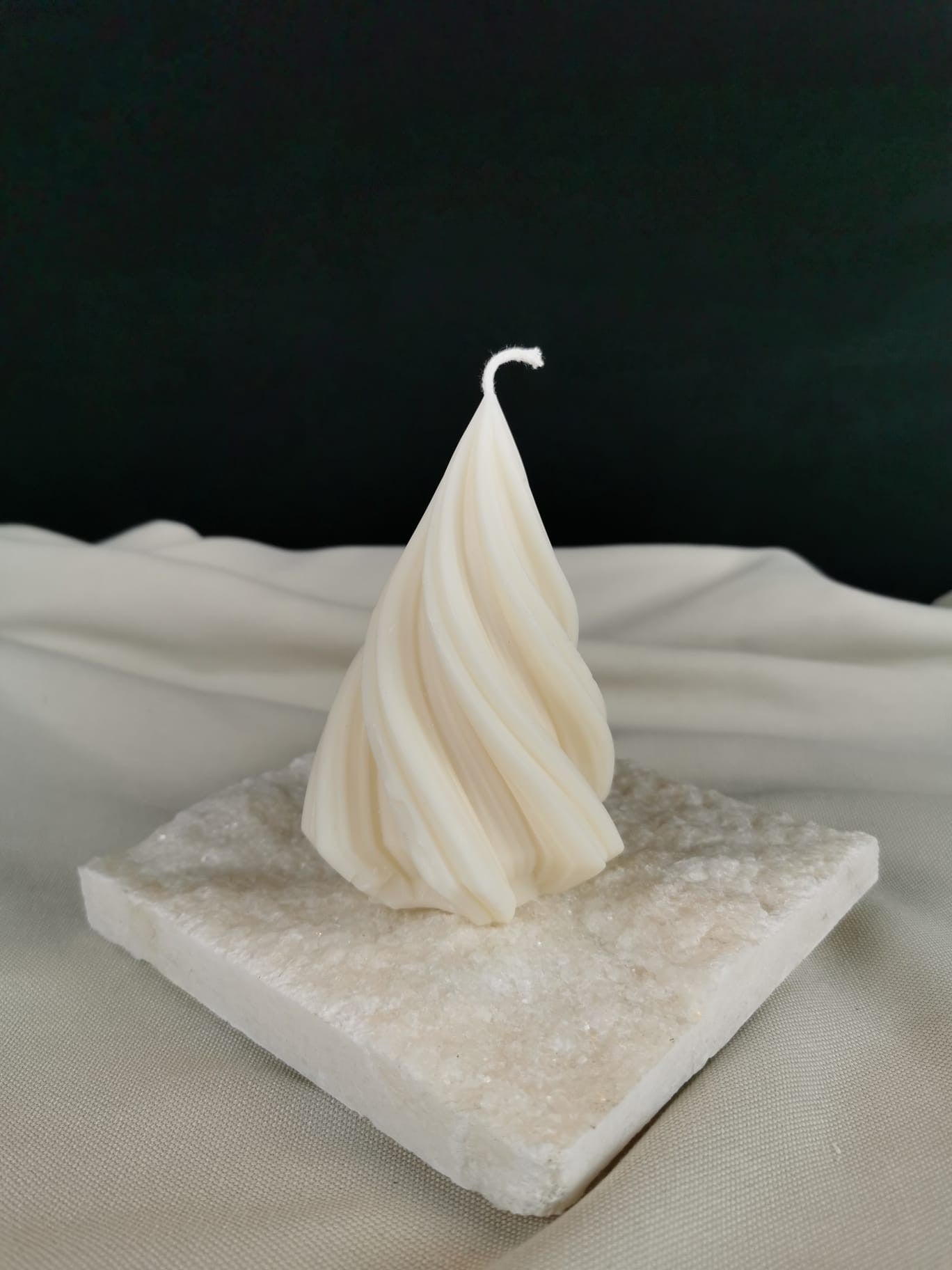 „Kleine gedrehte Baumkerze aus natürlichem Rapswachs, cremefarben, handgegossen, dekorativ auf einer Steinplatte präsentiert.“