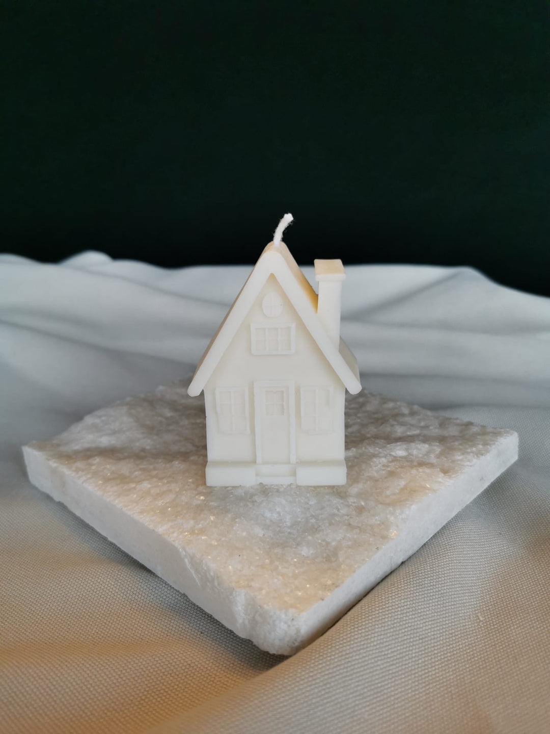 Handgegossene Rapswachskerze in Häuschenform auf weißer Dekoplatte – nachhaltige Naturwachskerze von Mara’s Kreativkischdle.