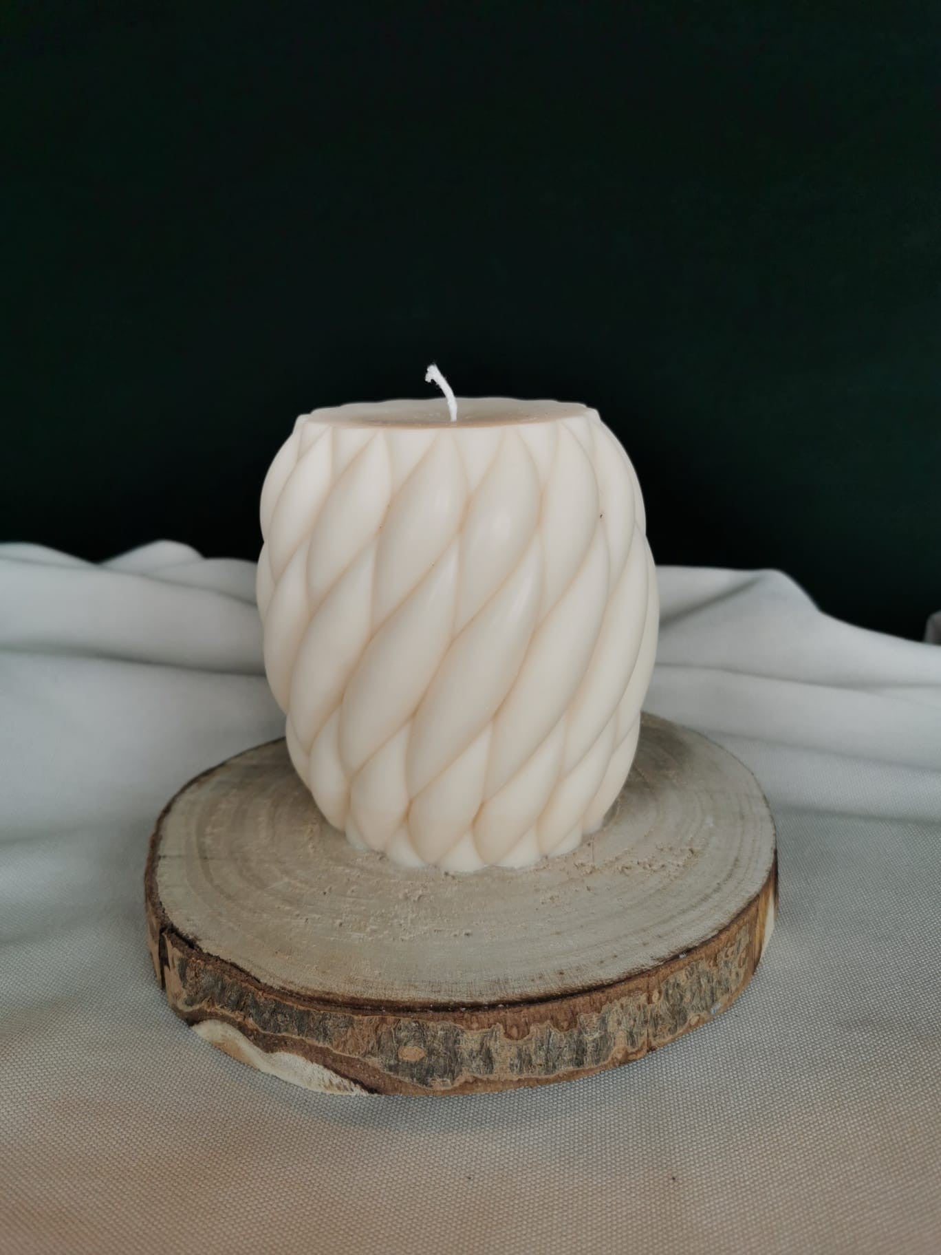 Gedrehte handgegossene Rapswachskerze „Twist Cup“ aus natürlichem Rapswachs, auf Holzscheibe präsentiert