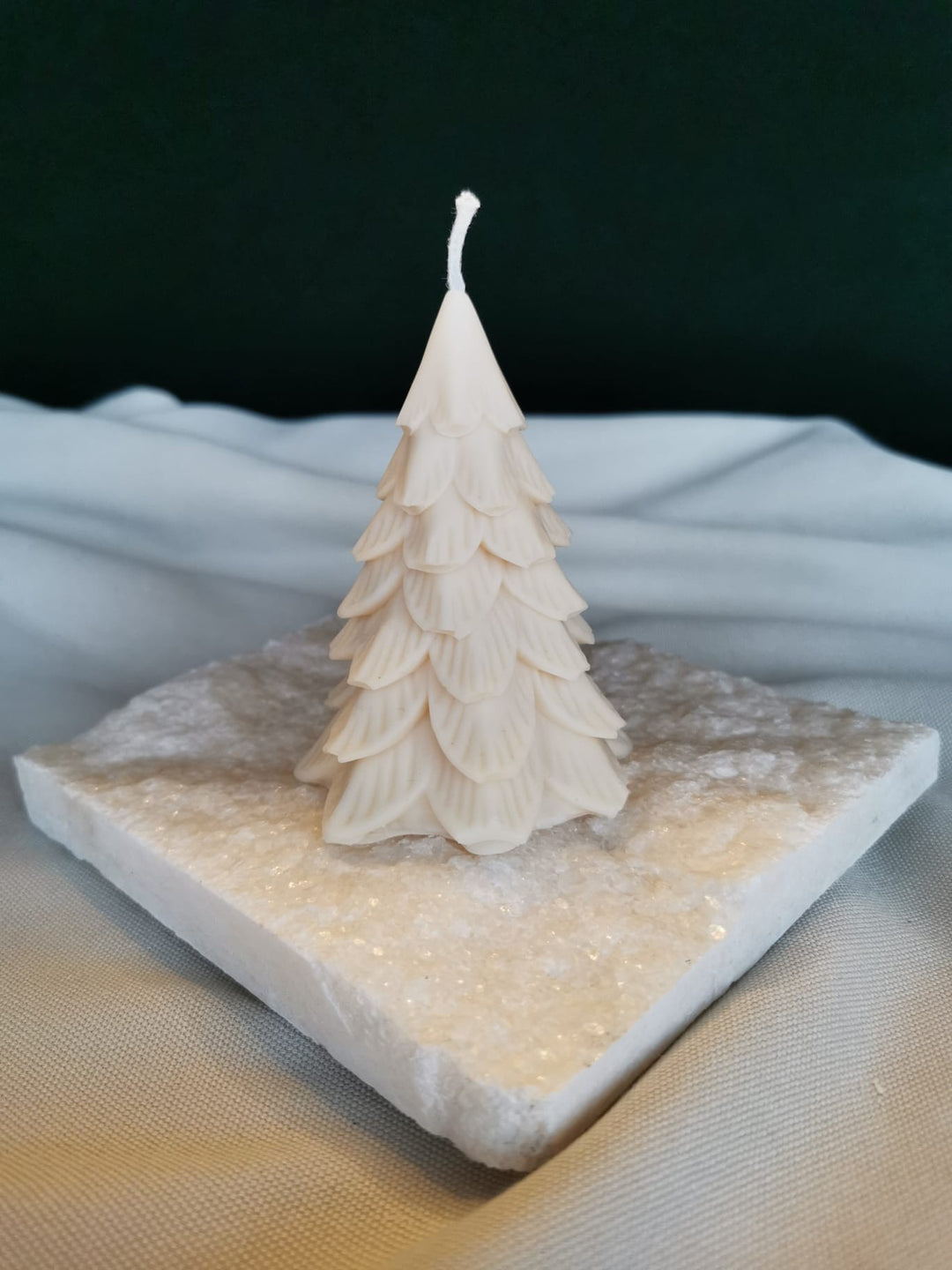 Handgemachte Rapswachskerze in Tannenbaumform aus veganem Bio-Rapswachs, dekorativ auf Naturholz präsentiert.