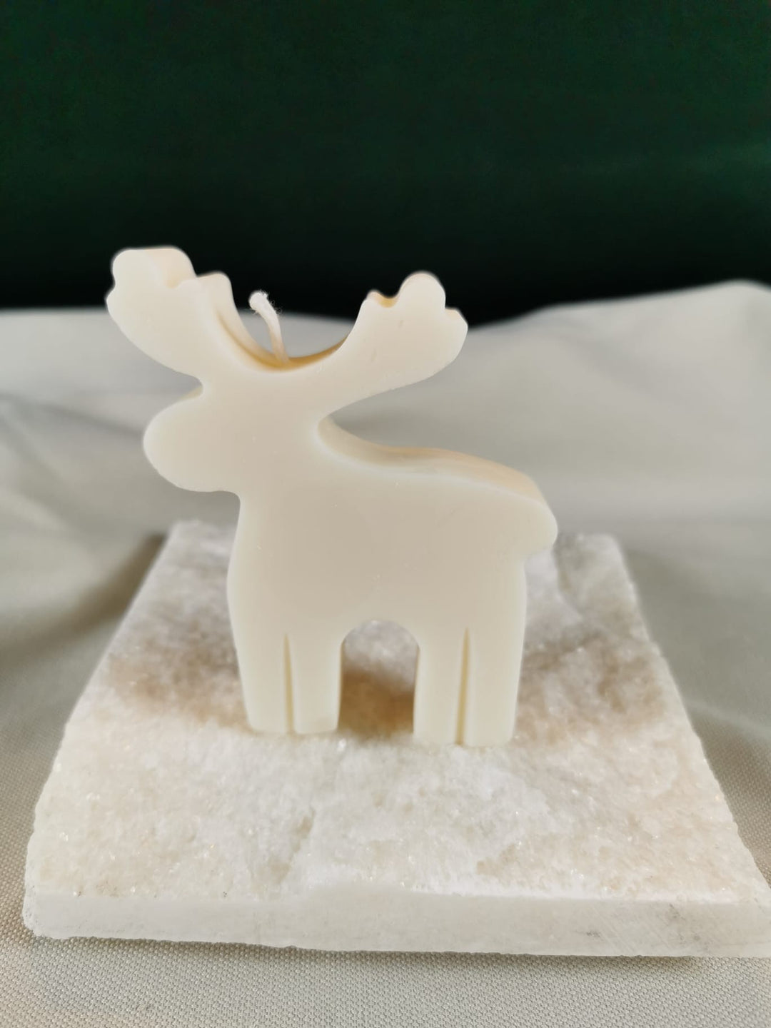 Handgegossene Rentier-Figurenkerze aus hellem Rapswachs, schlichtes skandinavisches Design, präsentiert auf einer hellen Steinplatte.