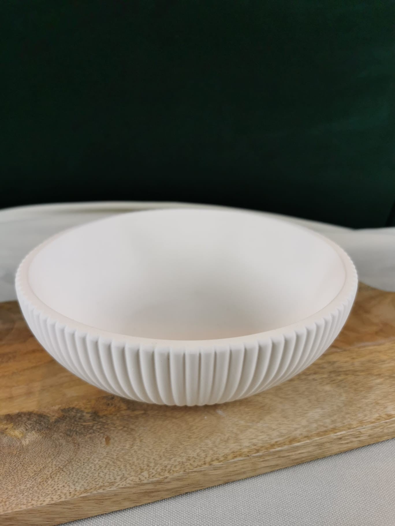 „Runde weiße Dekoschale mit Rillenstruktur auf Holzuntergrund – moderne handgefertigte Wohndeko.“