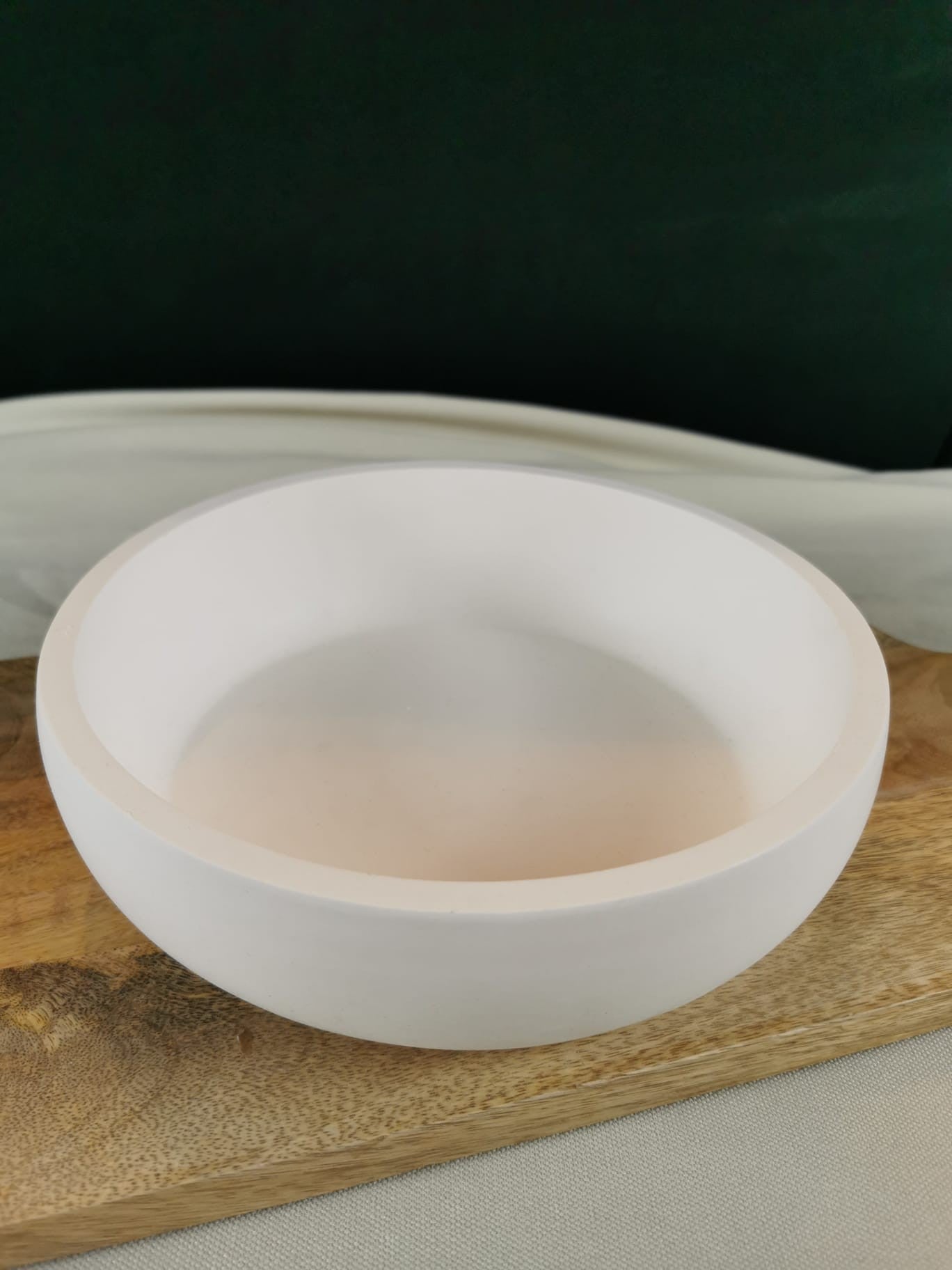 „Runde weiße Dekoschale auf Holzuntergrund – moderne minimalistische handgefertigte Schale.“
