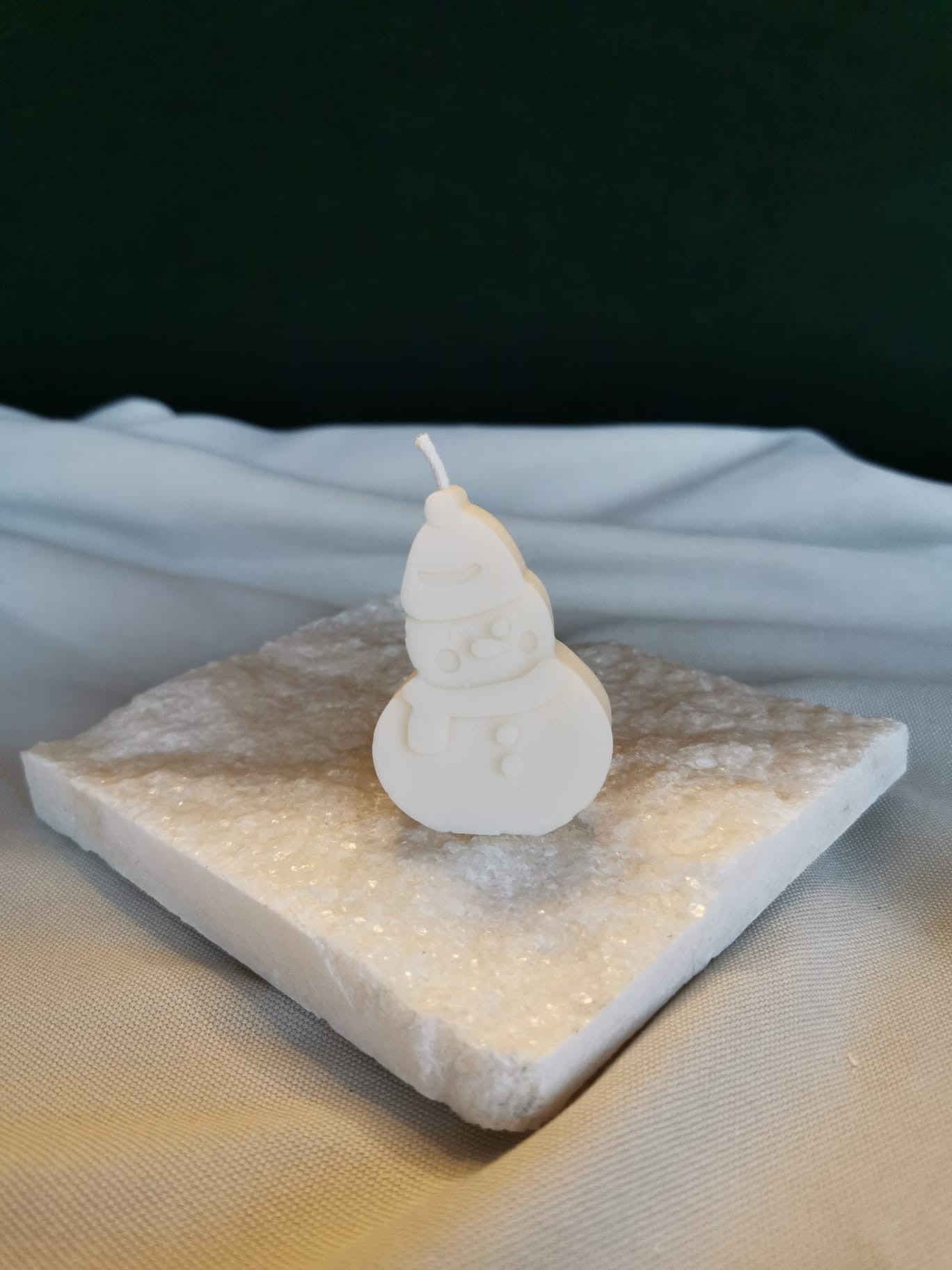 Handgegossene Schneemann-Kerze aus naturreinem Rapswachs auf einer weißen Marmorplatte, minimalistisch dekoriert im Winterstil.