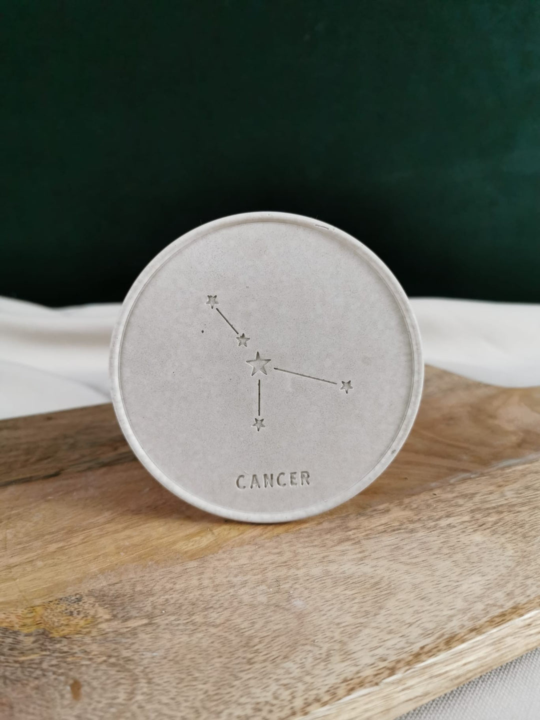 „Handgefertigter Beton-Untersetzer mit filigran eingraviertem Sternzeichen Cancer auf natürlicher Holzplatte präsentiert.“