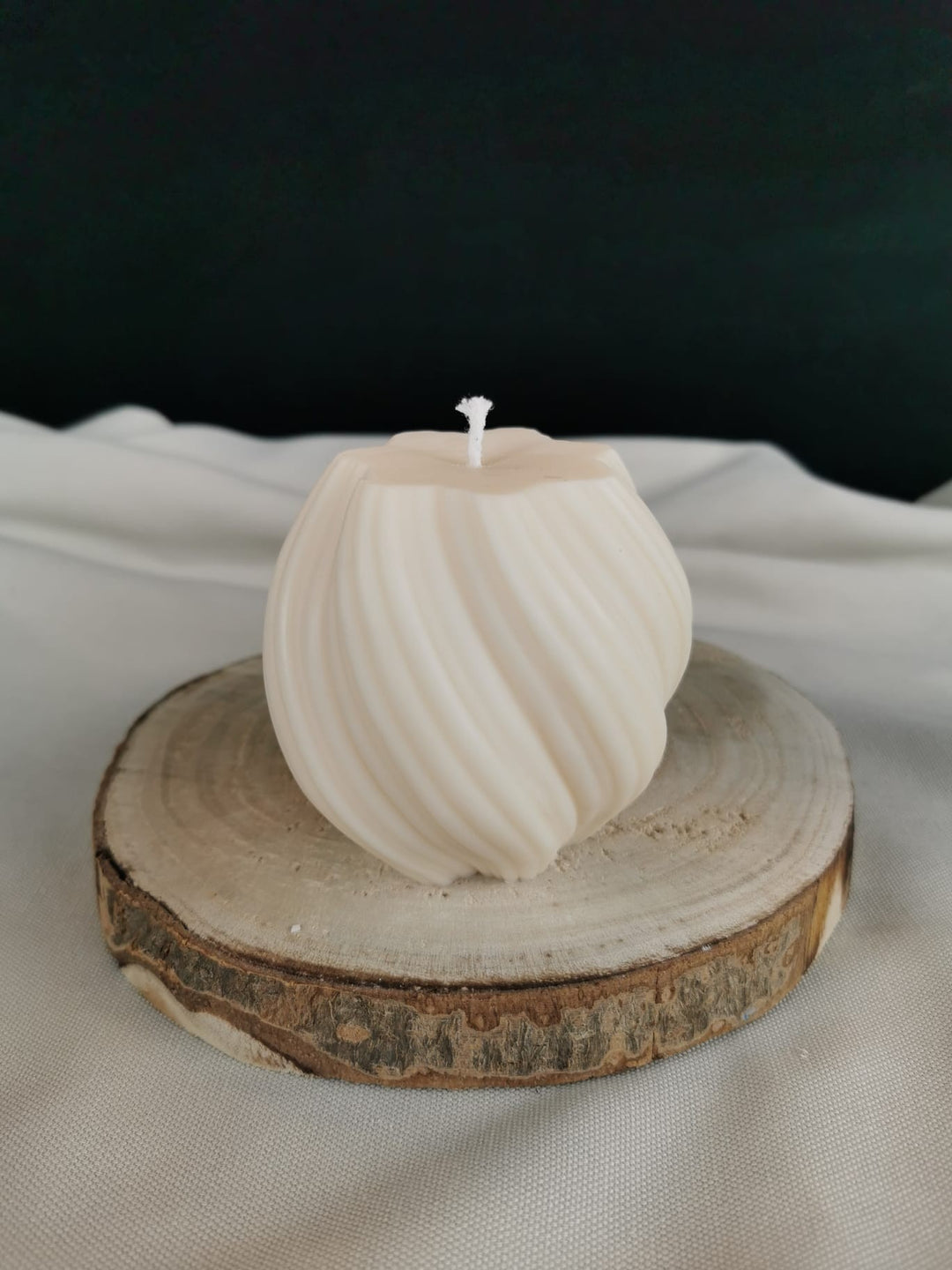„Handgefertigte runde Swirl-Dekokerze aus Rapswachs in natürlichem Cremeweiß, gedrehte Struktur, fotografiert auf einer Holzscheibe.“