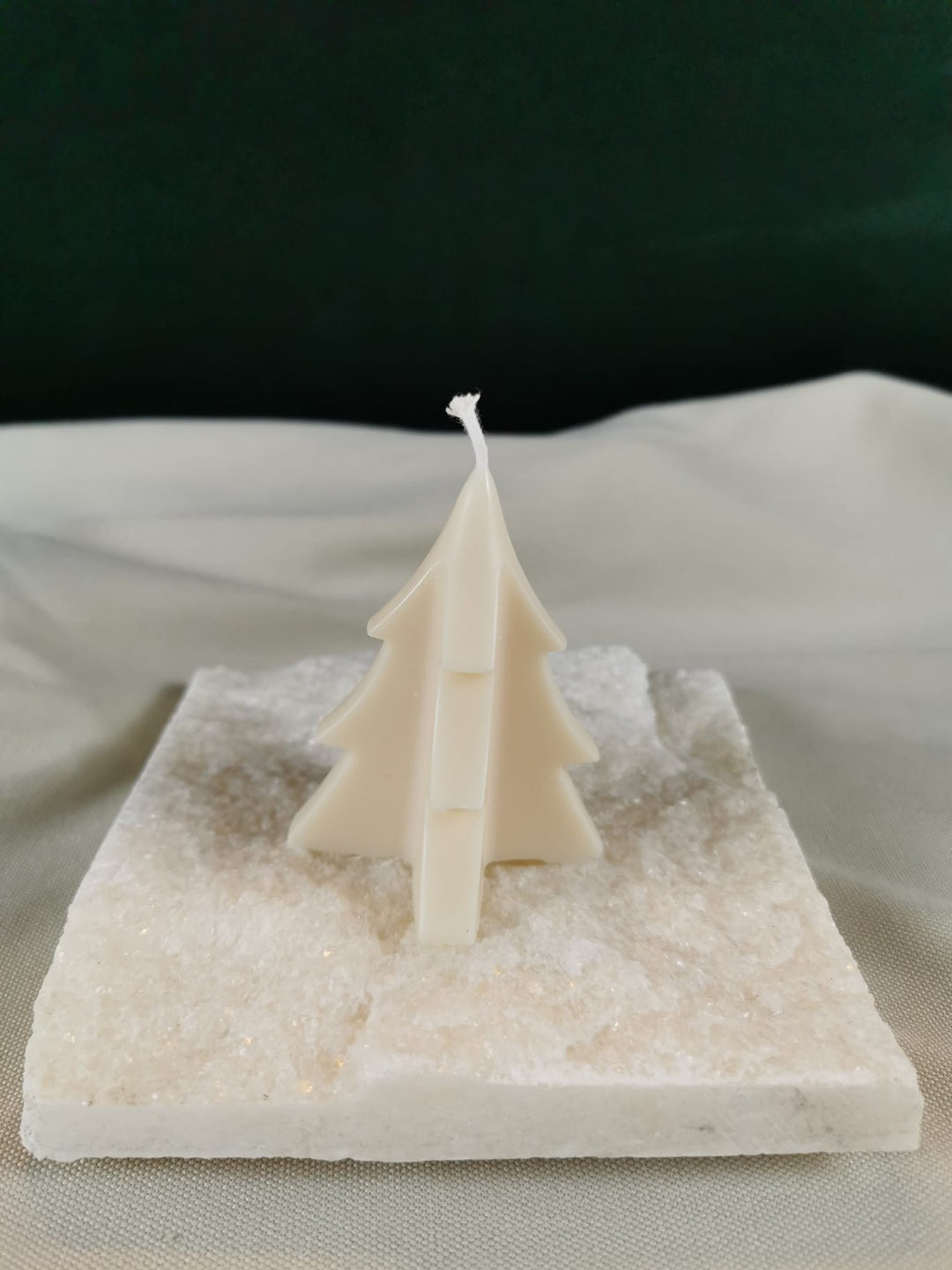 Handgegossene Tannenbaum-Kerze aus hellem Rapswachs in minimalistischem Design, dekorativ auf einer hellen Steinplatte präsentiert.