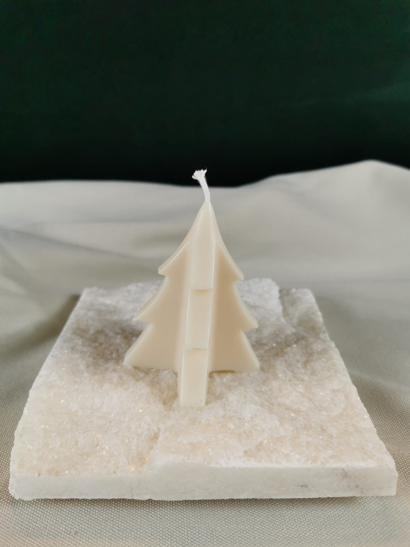 Handgegossene Tannenbaum-Kerze aus hellem Rapswachs in minimalistischem Design, dekorativ auf einer hellen Steinplatte präsentiert.