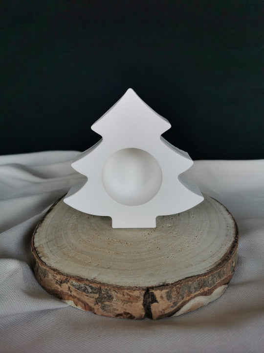 Weißer Kerzenhalter in Tannenbaumform aus Gießkeramik, dekorativ auf einer Holzscheibe präsentiert.