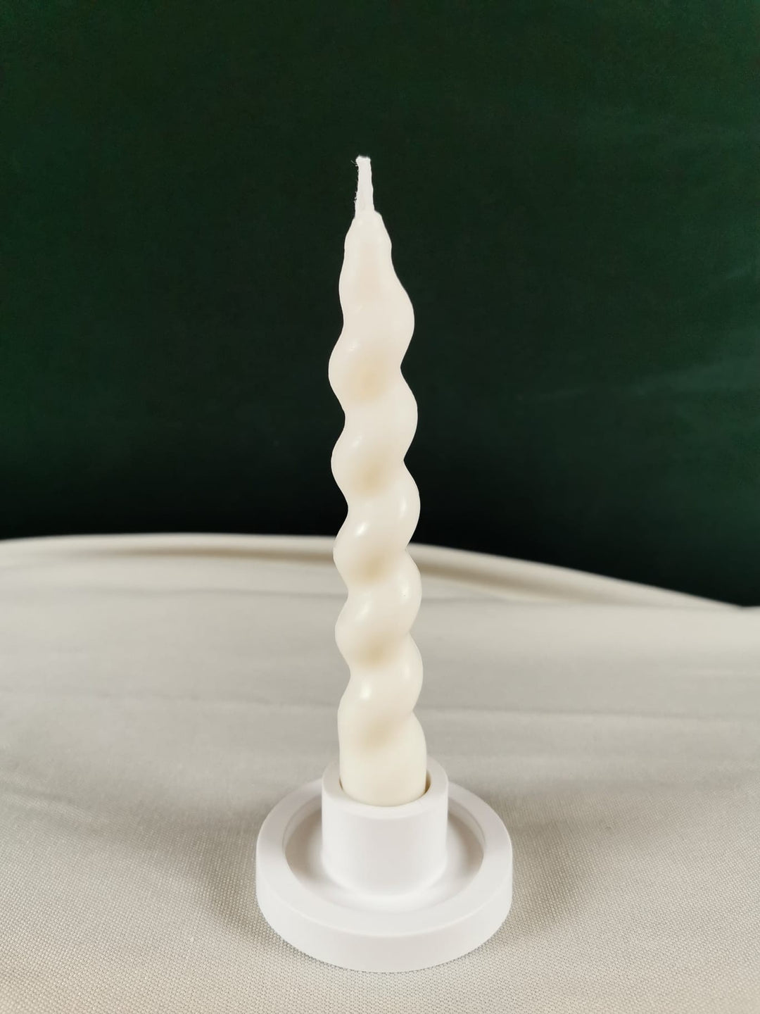 Handgefertigte cremefarbene Weihnachtskugel-Kerze aus nachhaltigem Rapswachs mit feinen Ornamenten, dekorativ auf einer Steinplatte präsentiert.